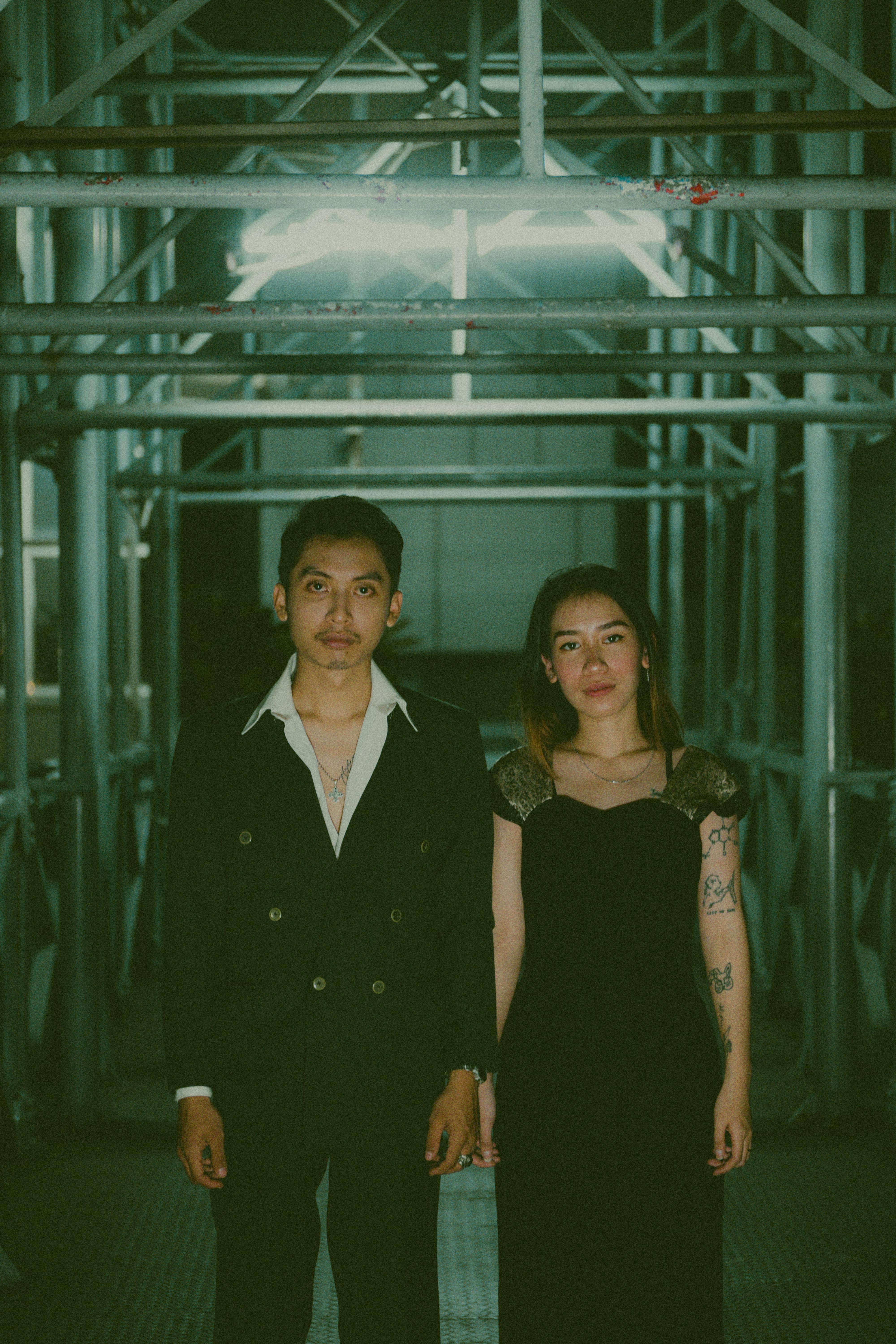 Elegant young couple in formal attire standing in an industrial corridor.
