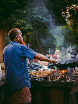 South Asian man cooking snacks on a street in Dhaka, capturing urban street life.