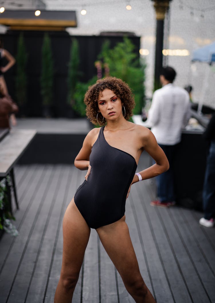 A Curly-Haired Woman In Black Bathing Suit Posing