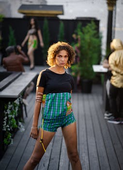 Outdoor photoshoot featuring a confident model in stylish attire on a wooden deck with blurred background.