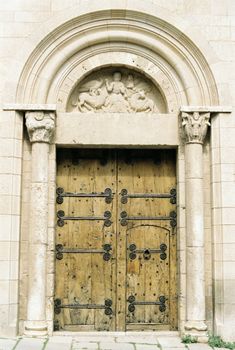 Stone archway with intricate carvings above a rustic wooden door, showcasing historic architecture.