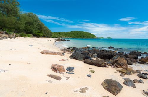 Free Peaceful beach scene with turquoise waters, rocks, and lush greenery in Thailand. Stock Photo