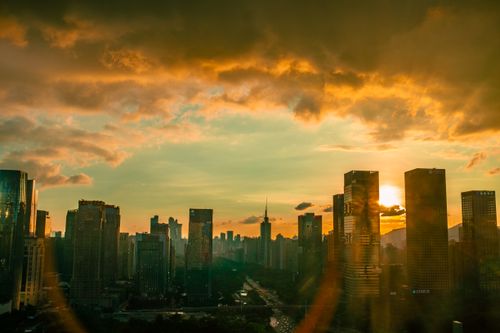 Free Stunning view of Shenzhen's skyline during golden hour with dramatic clouds and sun setting. Stock Photo