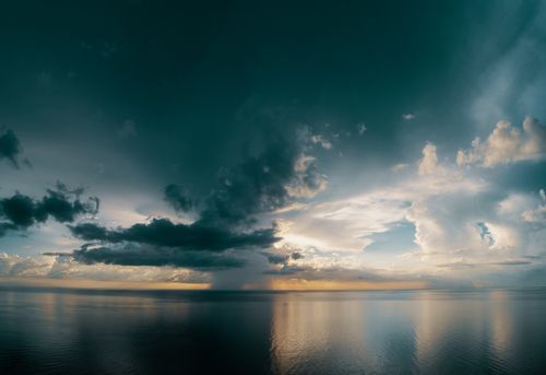 Free Breathtaking view of a dramatic cloudscape reflecting over a serene ocean during sunset. Stock Photo