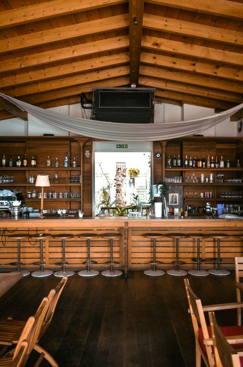 Free Interior view of a rustic bar with wooden decor, bar stools, and stocked shelves. Stock Photo