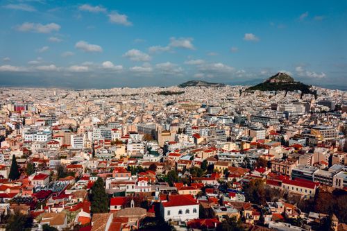 Free A breathtaking aerial view of Athens, showcasing its sprawling cityscape and the stunning Lycabettus Hill under a blue sky. Stock Photo