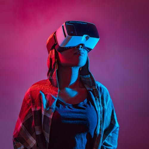 A woman wearing a vr headset in front of a pink background