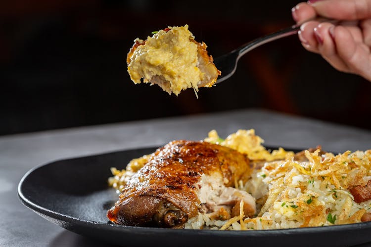 Chicken And Rice On A Black Ceramic Plate