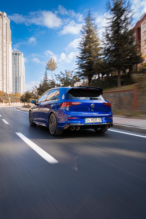Free Blue sports car speeding on an urban street in Istanbul, Turkey, with city buildings in the background. Stock Photo
