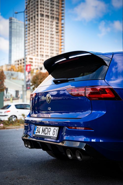 Free Rear view of a blue Volkswagen car parked in a city, with urban high-rises in the background. Stock Photo