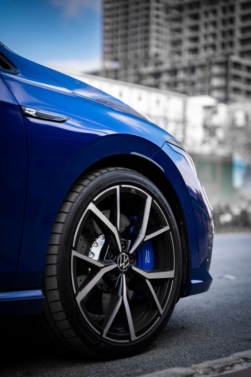 Free Close-up of a blue car's alloy wheel parked on a city street, emphasizing automotive design. Stock Photo