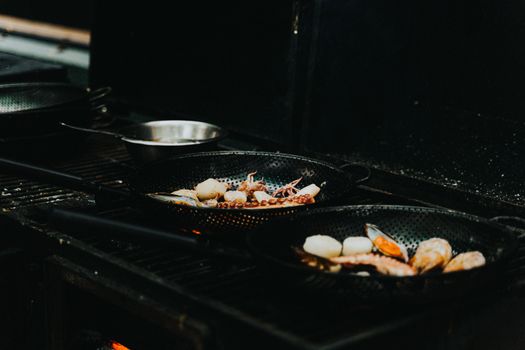 Close-up of seafood being cooked in pans on a stove, showcasing gourmet preparation.