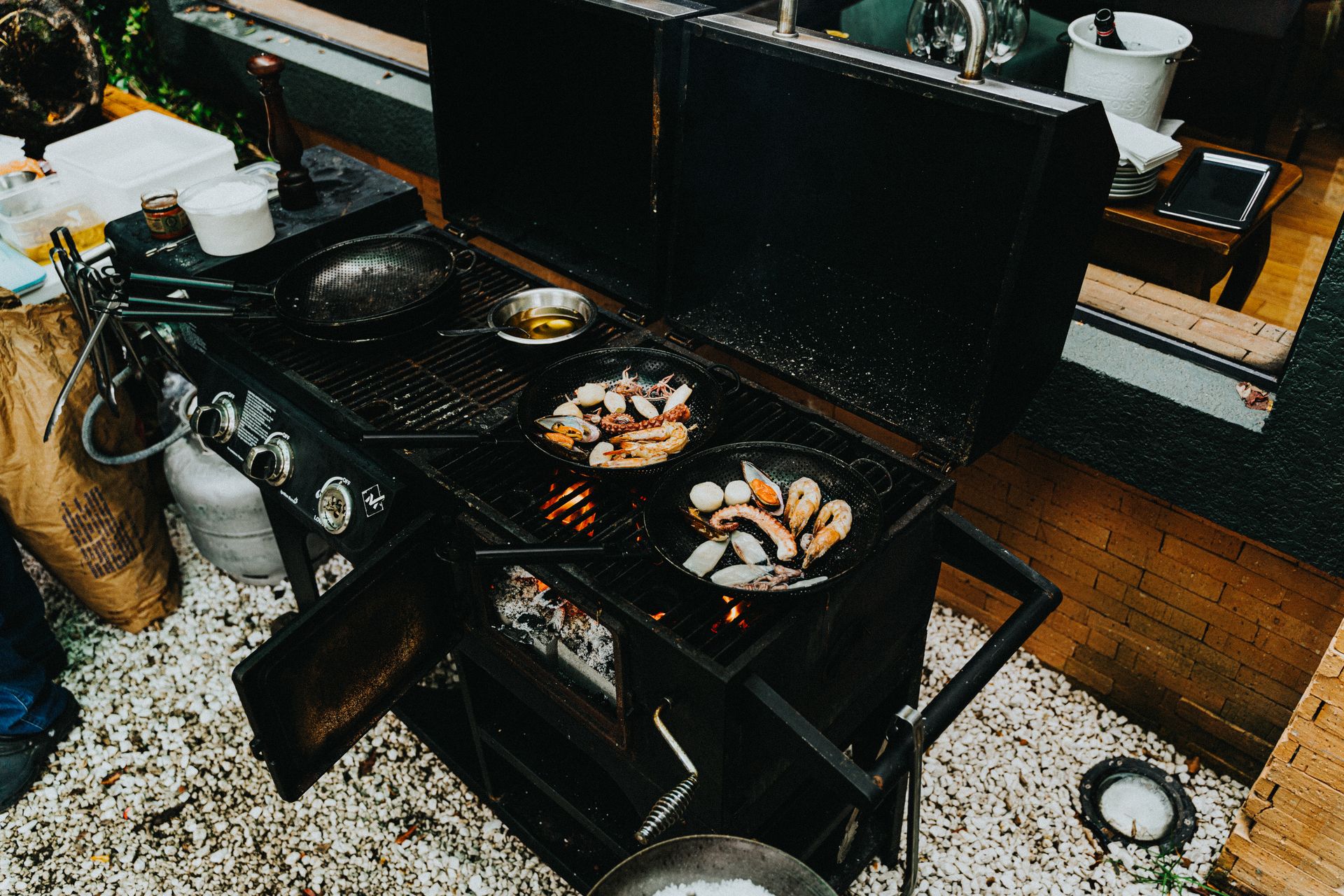 An outdoor barbecue grill with prawns and seafood cooking in cast iron pans. Perfect for a delicious meal.