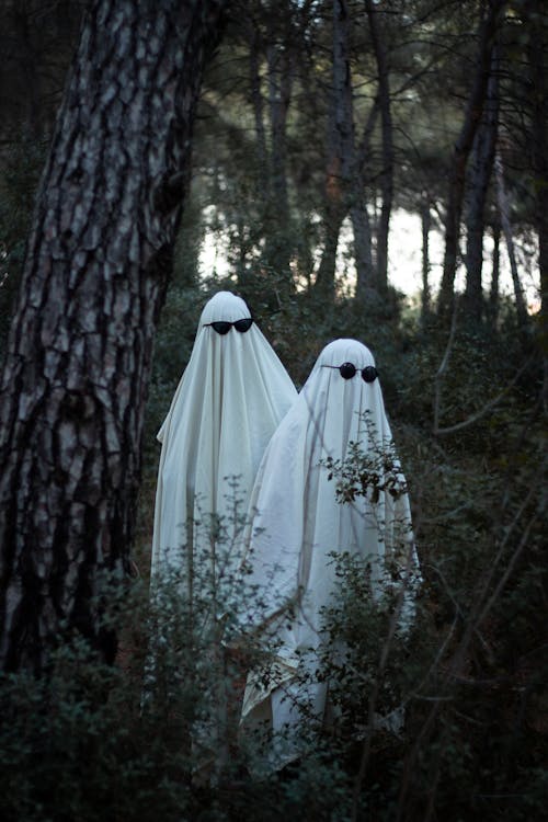 View of People Dressed as Ghosts Wearing Sunglasses Standing in a Forest 