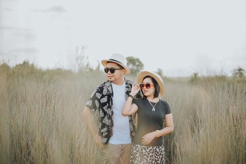 Couple in Hats and Sunglasses Posing in Field