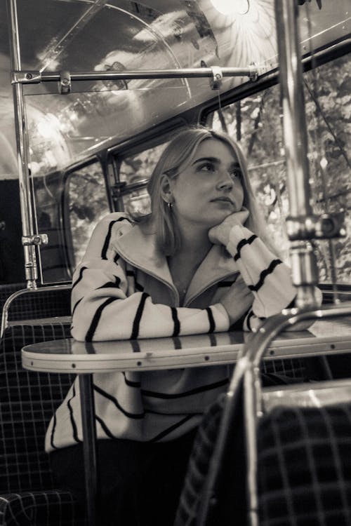 Grayscale Photo of a Woman Sitting at the Table