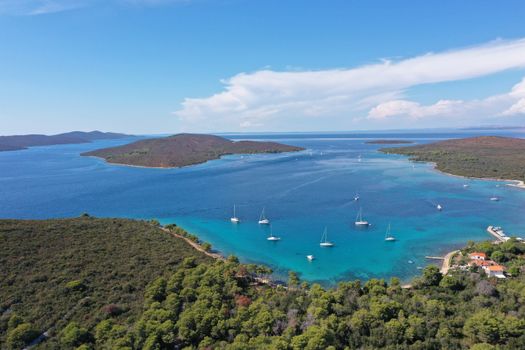 Aerial view of sailboats anchoring near Croatia's lush coastline and blue waters.