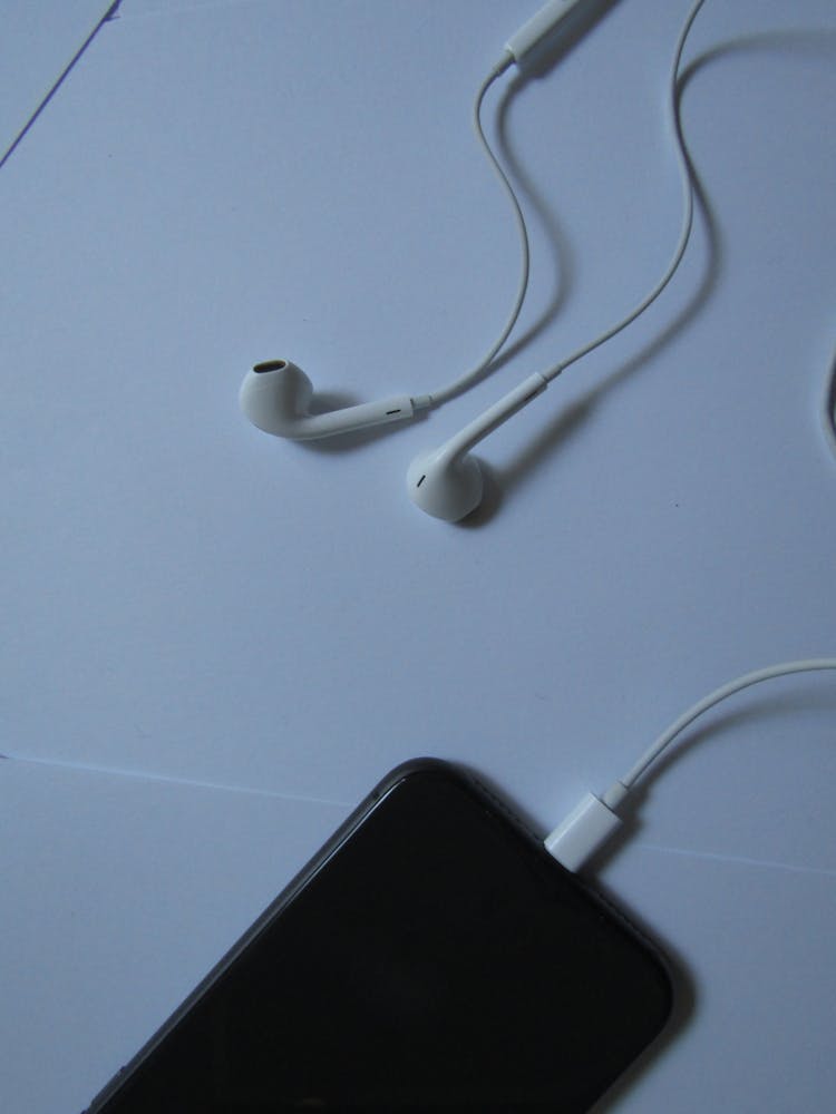 A Close-Up Shot Of Wired Earphones Plugged In A Smartphone