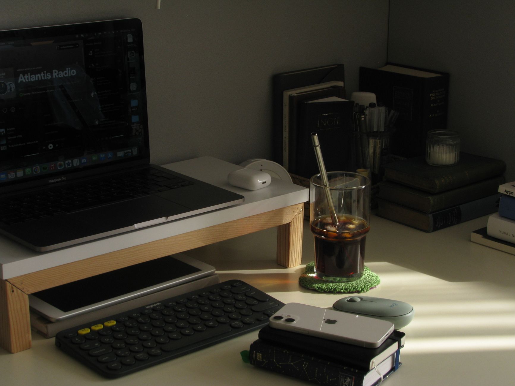 A cozy workspace with a laptop, keyboard, books, and a refreshing beverage.