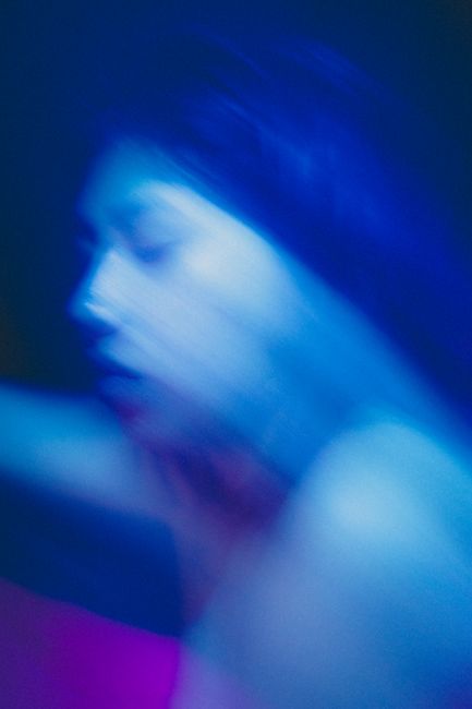 Artistic portrait using motion blur and blue lighting to create an abstract effect.
