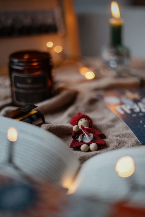 Free Warm and inviting Christmas setup featuring a small doll, candle, and festive decorations for a cozy atmosphere. Stock Photo