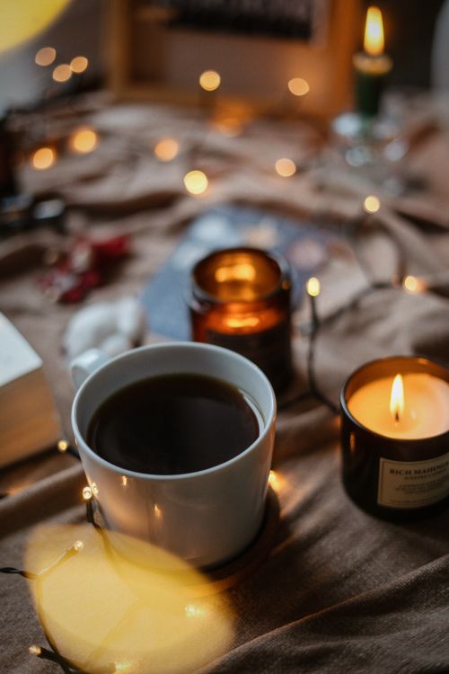 Free Warm and inviting scene with a hot coffee cup surrounded by candles and bokeh lights, perfect for relaxation. Stock Photo