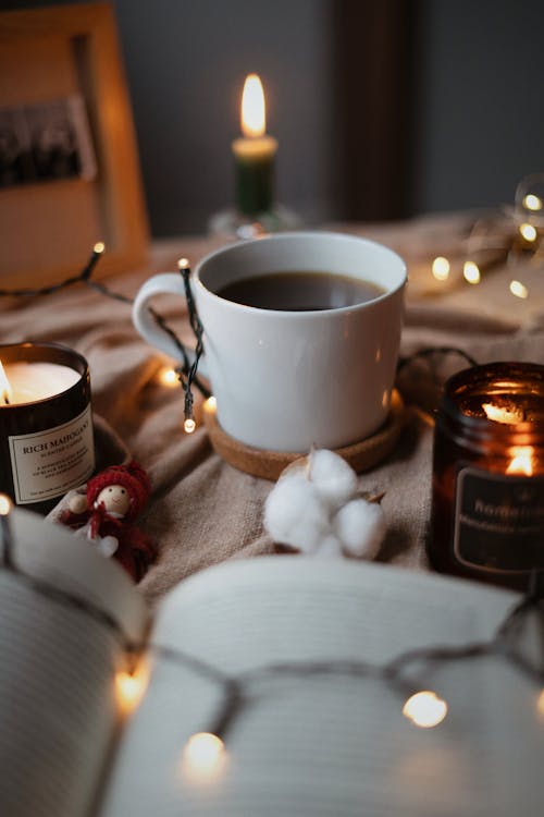 Free A Cup of Coffee Surrounded with Lighted Candles in Close-up Photography Stock Photo