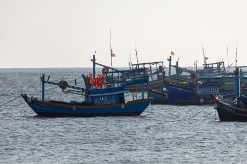 Free Traditional fishing boats anchored on the tranquil ocean with clear skies above. Stock Photo