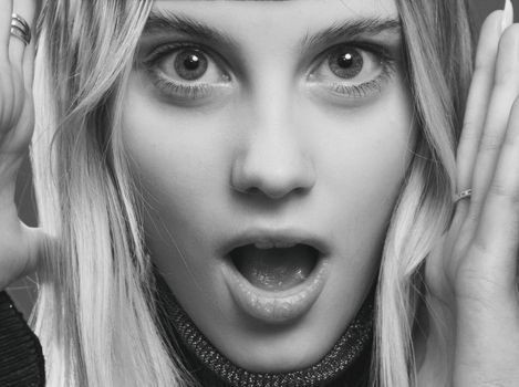 Close-up black and white portrait capturing a surprised expression of a young woman.
