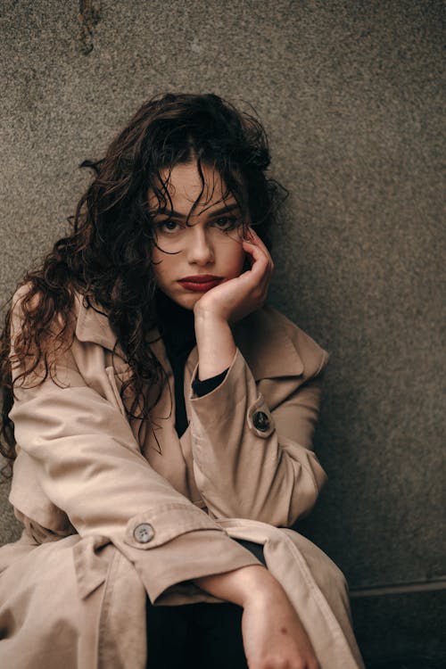 Beautiful Woman in Brown Coat with Hand on Chin