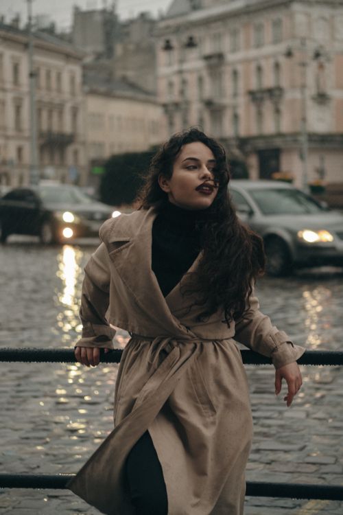 Young woman in beige trench coat on a vintage city street