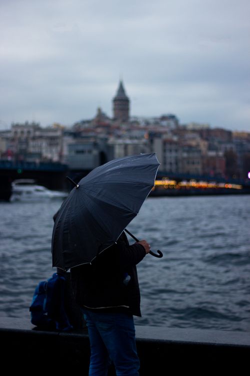 Free Person with umbrella by the waterfront in Istanbul, with Galata Tower in the background. Stock Photo