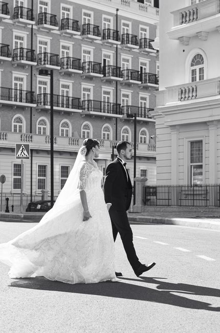 Black and white photo of a bride and groom walking in a city setting.