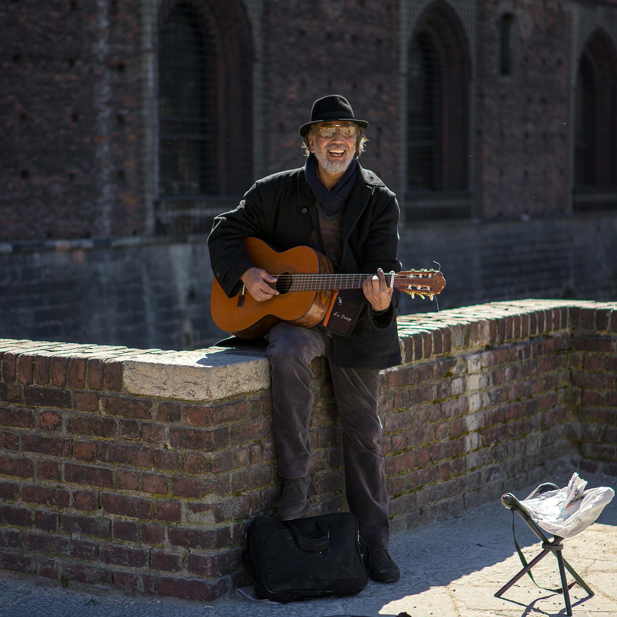 a smiling man playing guitar on the street