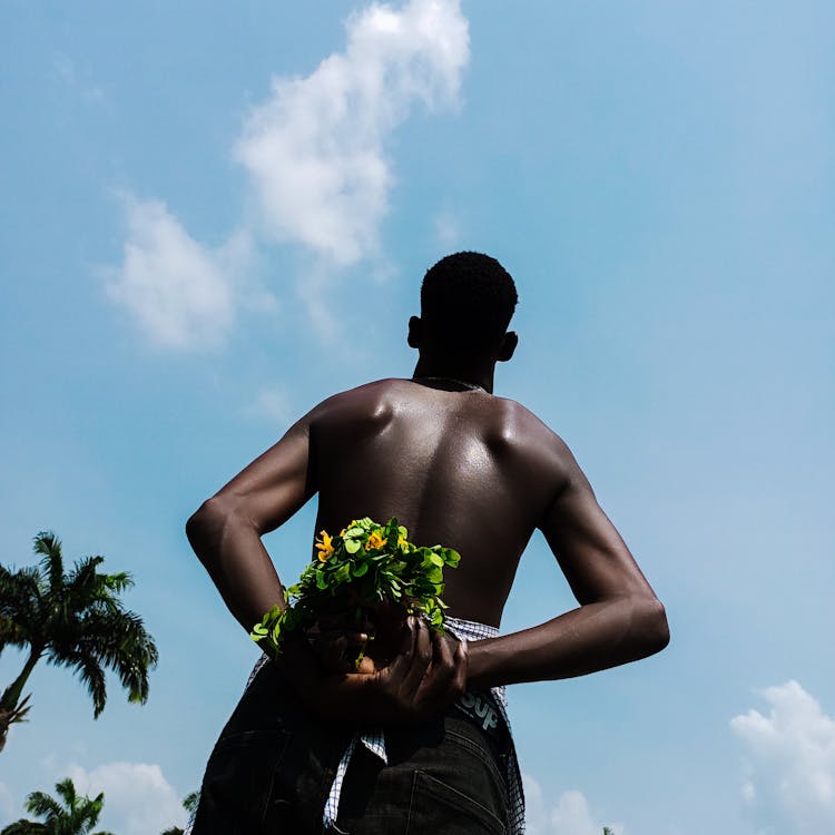 Low Angle Shot Of A Man Holding Flowers Behind His Back