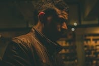 室内灯光阴沉，一位穿着皮夹克的时尚男子侧面图