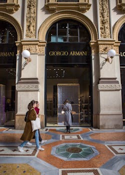 Stylish individuals walking past the ornate Giorgio Armani entrance in a luxury shopping gallery.