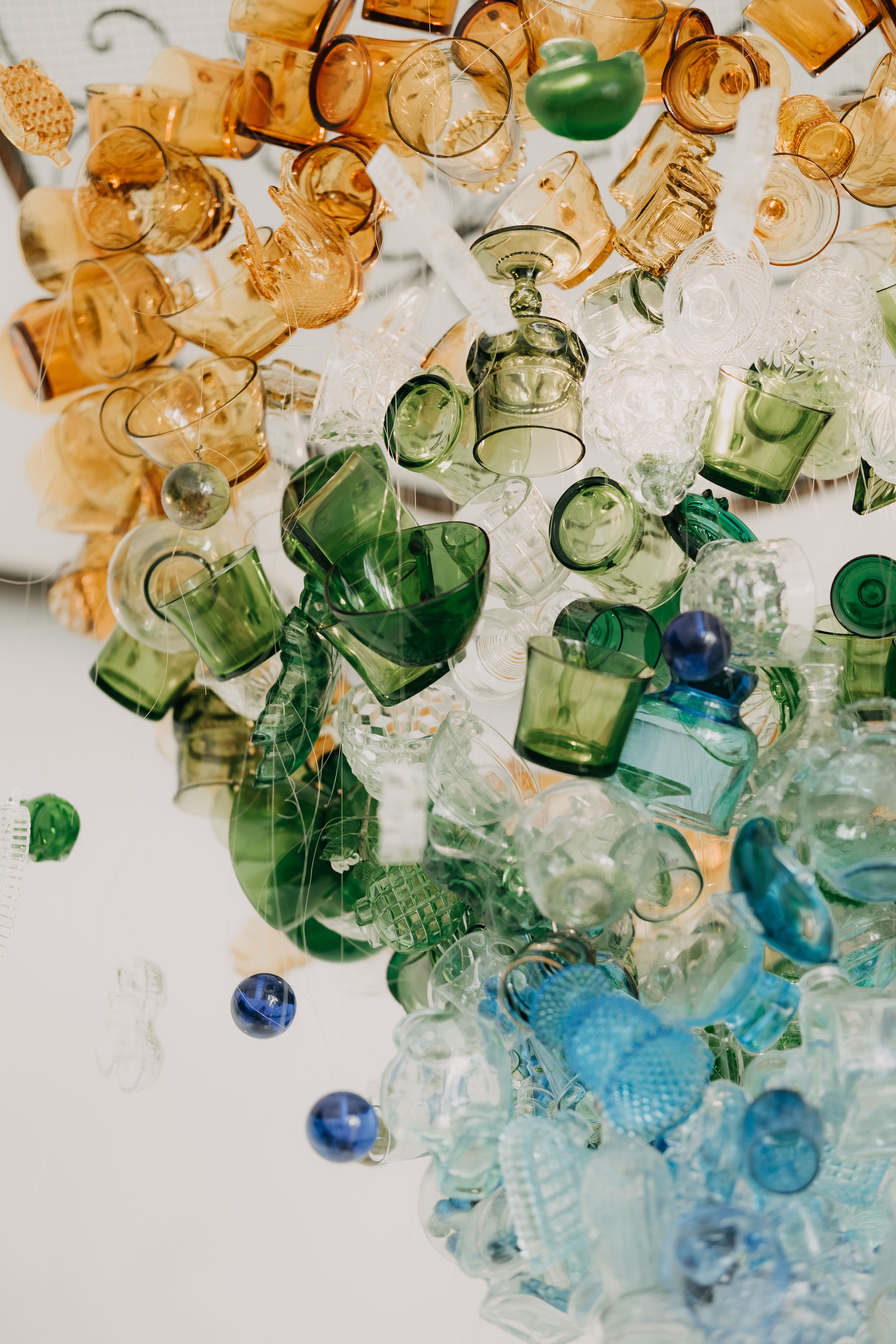 Artistic display of colorful glassware seen from above on a white background.