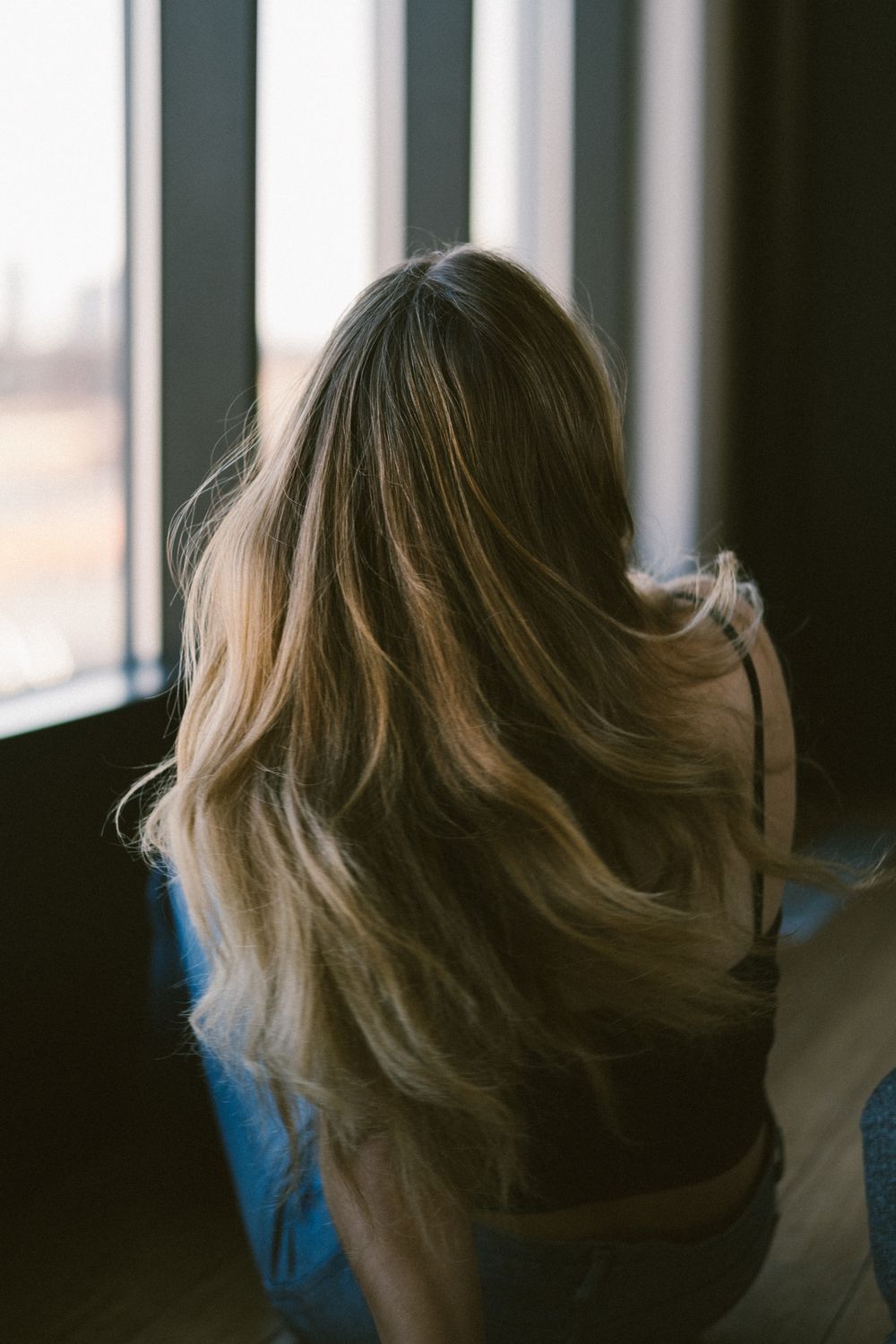 Lang blond haar in zachte lagen, van achteren gefotografeerd