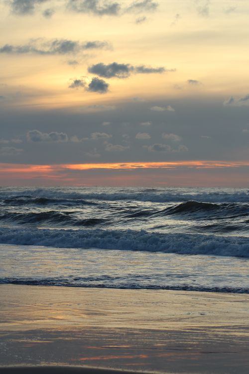 Free Calm ocean waves under a twilight sky with warm hues, perfect for serene and nature-themed designs. Stock Photo