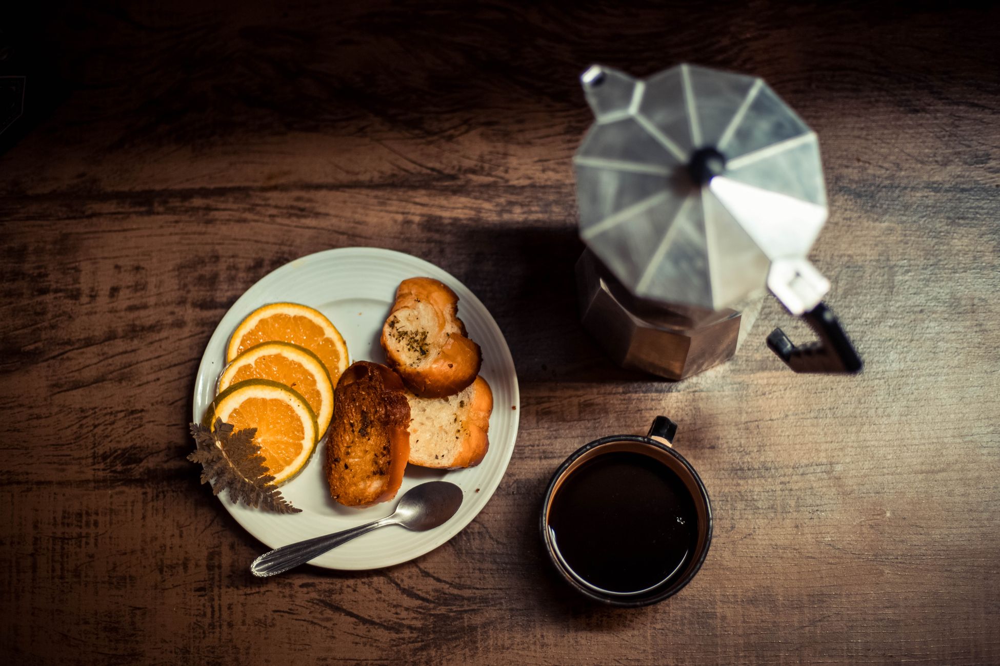 Warm breakfast scene with coffee, toast, and orange slices captured in an overhead shot.