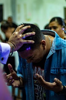 A man deeply immersed in a religious ceremony, hands placed on his head.