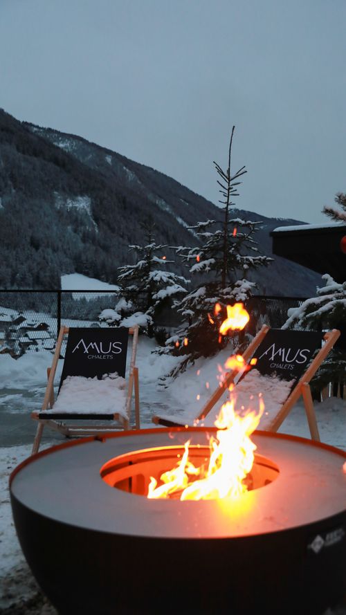 Free Warm fire pit on a snow-covered patio with mountain views, perfect for winter relaxation. Stock Photo