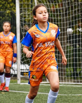 Girls in colorful soccer uniforms playing a lively match outdoors.
