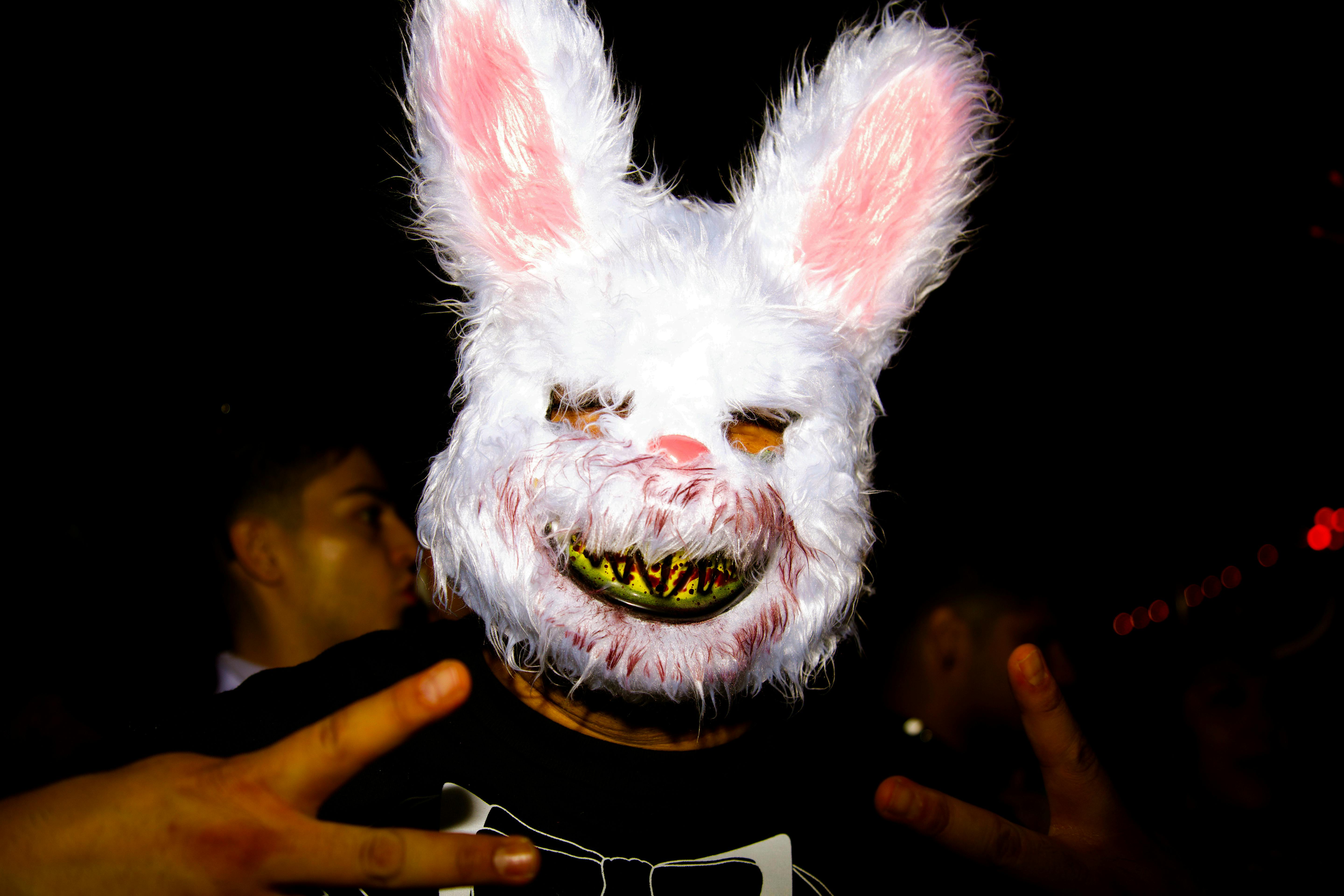Spooky bunny mask with eerie smile worn by an adult at a Halloween party.