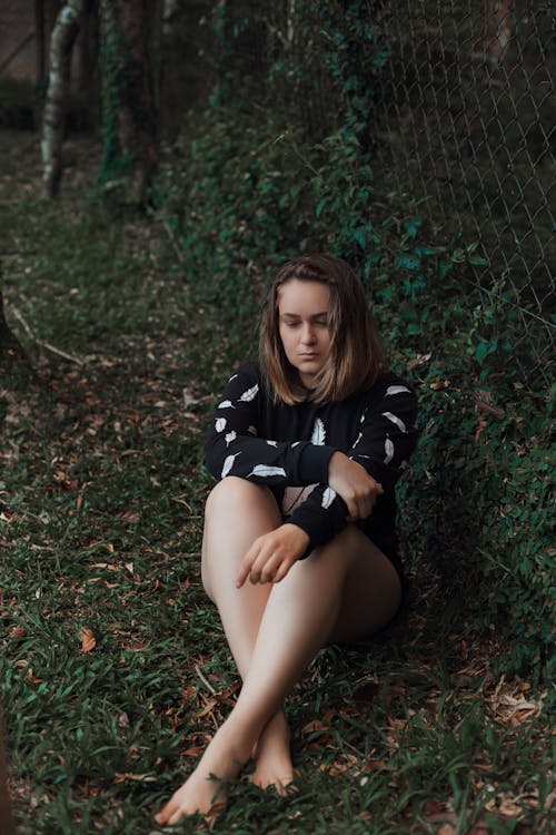 Woman Sitting on Grass Field Looking Sad