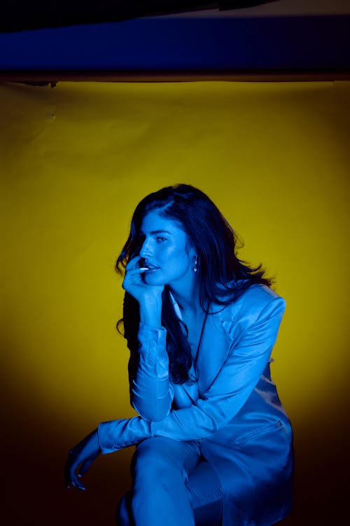 A Pretty Woman Wearing Blazer Sitting Near a Yellow Background