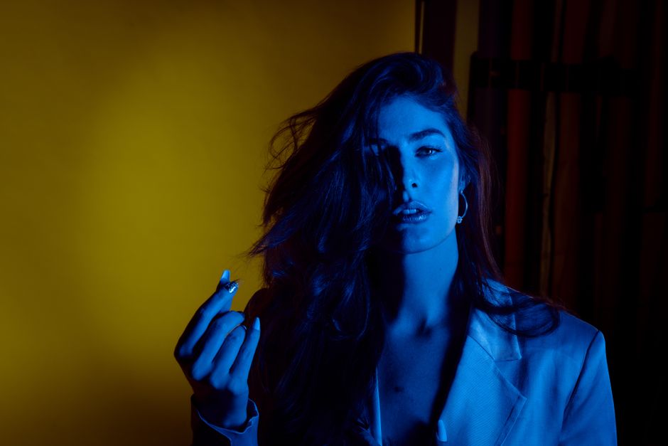 Stylish woman in moody blue and yellow lighting, creating a bold artistic portrait.