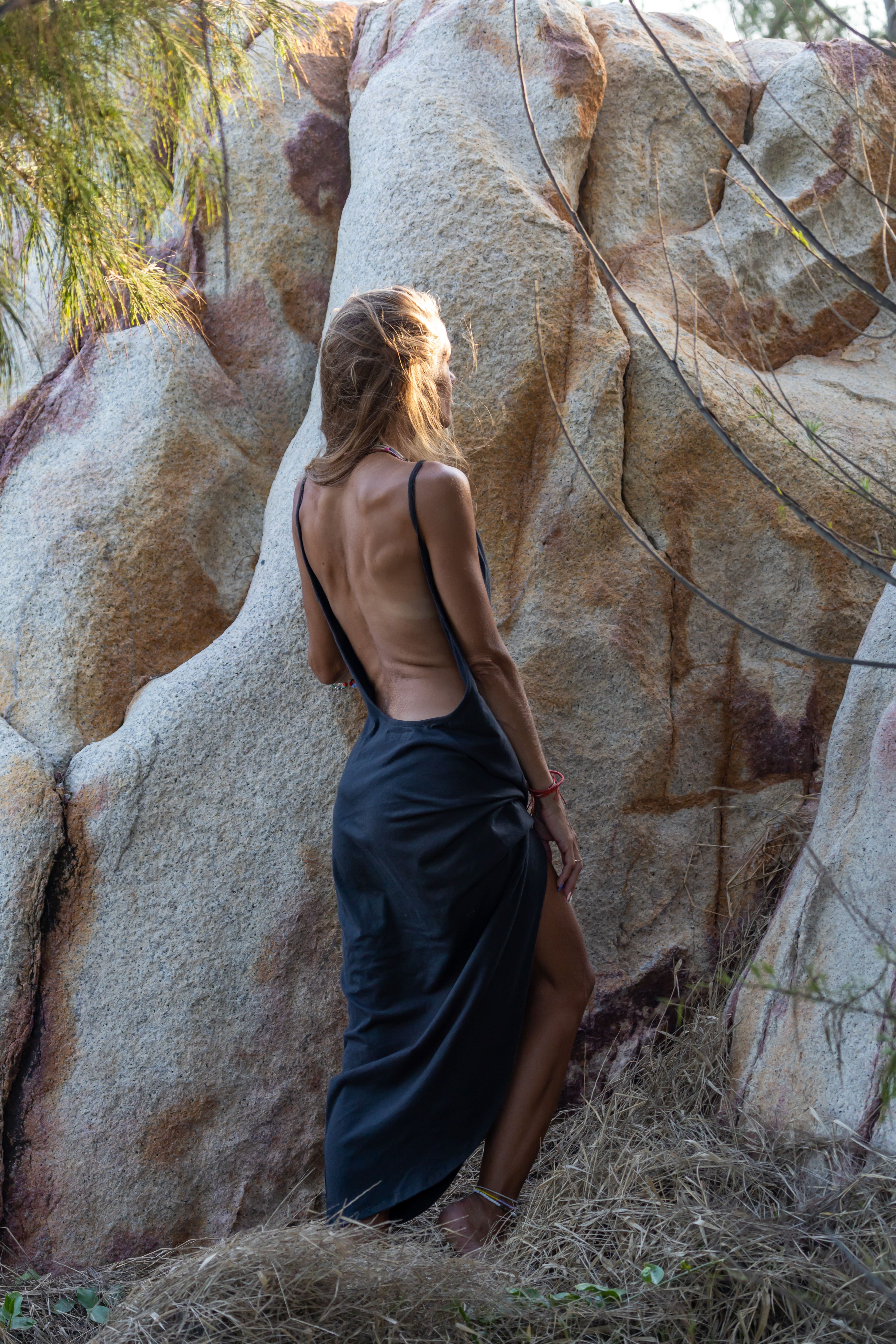 Woman in a Backless Dress Standing near Rock · Free Stock Photo