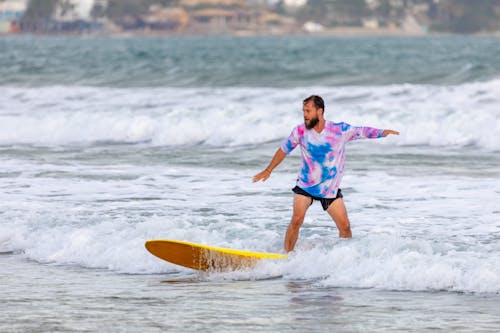 Photograph of a Man Surfing with a Yellow Surfboard